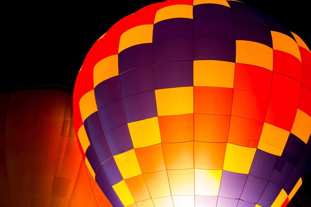 Image of a brightly colored hot air balloon against a dark night sky.